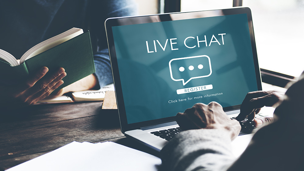 Mann som skriver på pcen og på pcen står det "live chat" 