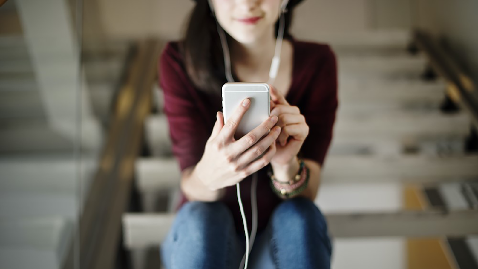 Bor_podcasting_inn_i_markedsforingsstrategien_din_Kvinne_paa_telefonen_som_horer_paa_podcast