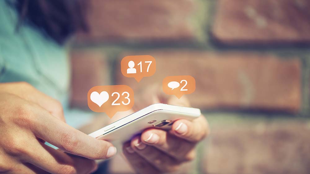 Dame som holder en mobil med notifications som kommer opp fra mobilen. 23 hjerter, 17 venneforespørsler og 2 meldinger. 