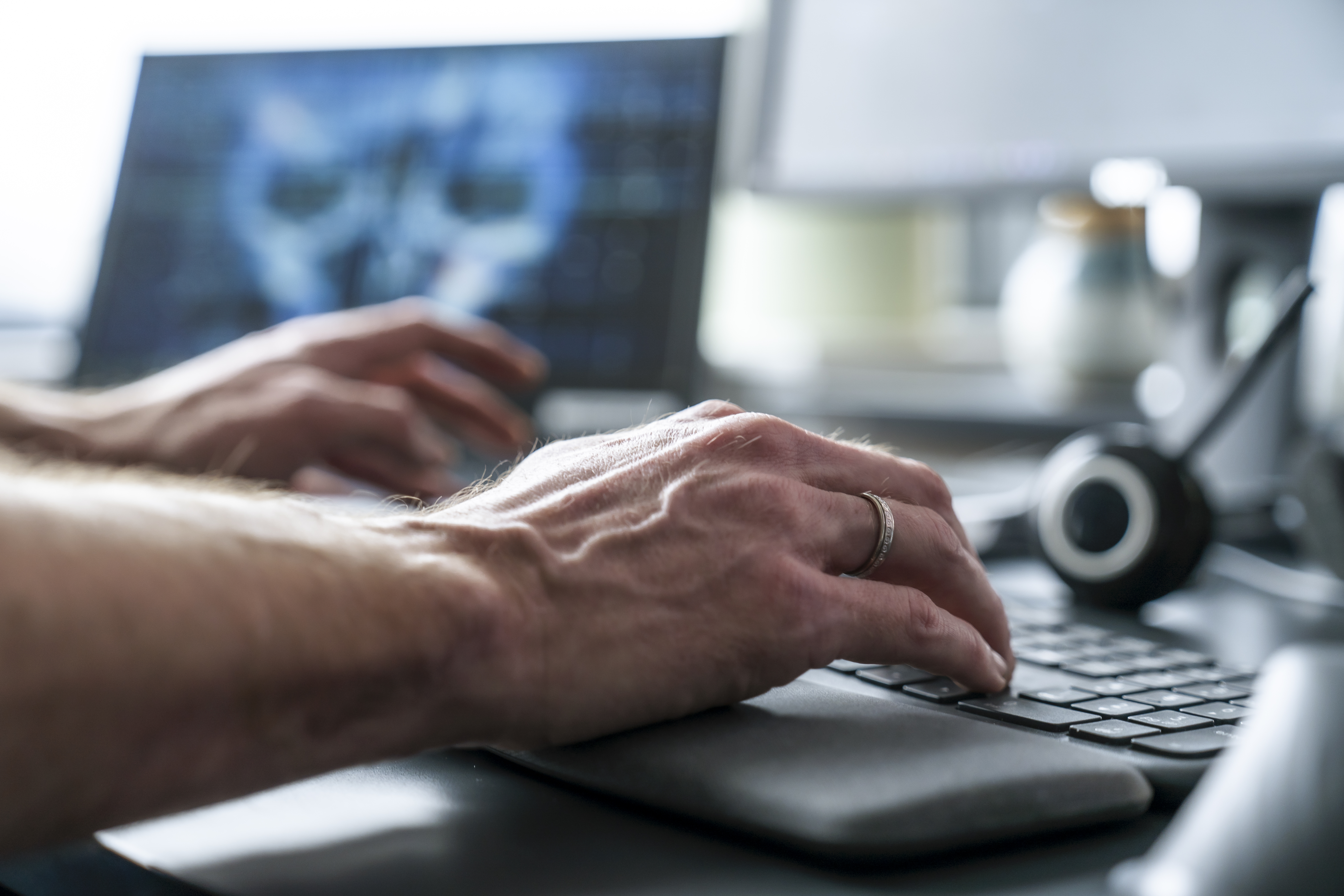 Nærbilde av hender med ring som skriver på tastatur